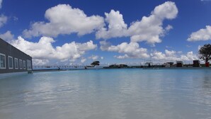 A swimming pool with a building on one side and a bridge in the background.