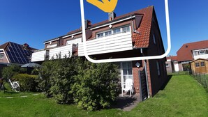 A two-story house with a red-tiled roof, a satellite dish, and solar panels.