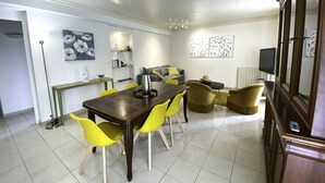 A dining area with a wooden table and yellow chairs, a grey sofa, and a television on a stand. - Villa Gai Soleil, quiet location 500 m from Port Santa Lucia and beaches (Saint-Raphaël)