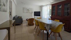 A dining area with a long table, yellow chairs, a grey sofa, and a TV. - Villa Gai Soleil, quiet location 500 m from Port Santa Lucia and beaches (Saint-Raphaël)