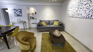 A modern living room with a grey sofa, yellow armchairs, a wooden coffee table, and a dining area with a dark wooden table and yellow chairs. - Villa Gai Soleil, quiet location 500 m from Port Santa Lucia and beaches (Saint-Raphaël)