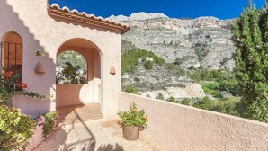 A building with a terracotta roof, a balcony with potted plants, and a view of rocky hills. - Semiramis 4 - Altea, Costa Blanca (Altea)