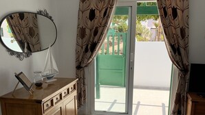 Una habitación con un armario de madera, un espejo, una maqueta de un velero y una puerta verde que da al exterior.