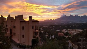 A large, multi-story building with a prominent tower, surrounded by a mountainous landscape and a sunset sky. - Semiramis 7 - Altea, Costa Blanca (Altea)