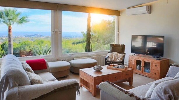 Ein Wohnzimmer mit großem Fenster, Fernseher und Holzschrank.
