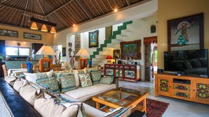 A spacious living area with a sofa, coffee table, and a television. A staircase with green steps leads to another level. - Hibiscus Guest Suitebest Breakfast in Bali (Ubud)