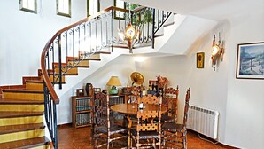 Un coin repas avec une table ronde et des chaises, un escalier avec une rampe en bois et des carreaux de sol à motifs.