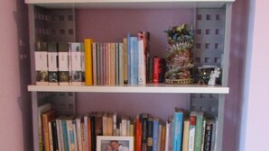 A bookshelf with multiple shelves filled with books, a small decorative item, and a figurine. - Wonderful Amalfi Coast Apartment Overlooking the sea With Free Wifi and Parking (Vietri sul Mare)