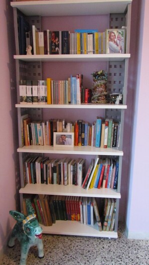 A bookshelf with multiple shelves filled with books, a small decorative item, and a figurine. - Wonderful Amalfi Coast Apartment Overlooking the sea With Free Wifi and Parking (Vietri sul Mare)