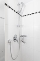 Eine Dusche mit Handbrause und Wandarmatur.