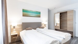 A hotel room with two beds, a large mirror, a painting, and a wardrobe. - Hotel Köln 2020 (Cologne)