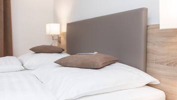 Ein ordentlich gemachtes Bett mit weißen und braunen Kissen, ein Holz-Kopfteil und ein Nachttisch mit einer Lampe.