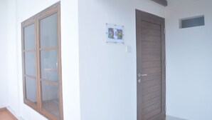 A room with a large window, a door, and a small wall-mounted artwork. - Frog House a Charming Apartment in Best Bali Location (Seminyak)