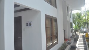 A white building with multiple windows and a covered outdoor area with steps leading to a door. - Frog House a Charming Apartment in Best Bali Location (Seminyak)