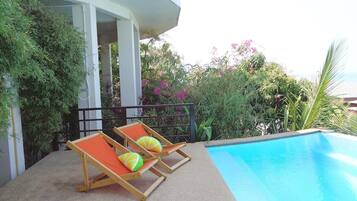 A pool area with two lounge chairs and a small pool.