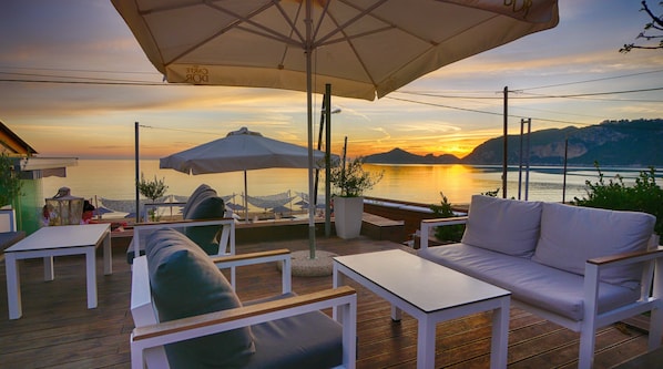 Une terrasse dotée d’un espace salon extérieur, comprenant un canapé et des fauteuils, ainsi que des parasols pour créer de l’ombre.