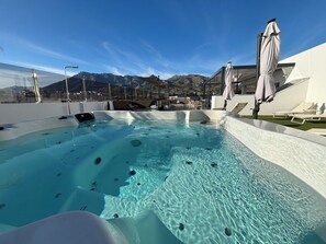 A pool with clear water, surrounded by lounge chairs and umbrellas, with mountains in the background. - DAOS Suites Terrace Marbella (Marbella)