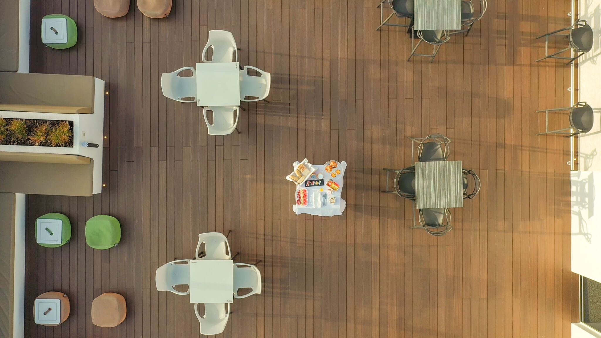An outdoor seating area with multiple tables and chairs, arranged in a circular pattern around a central table with a tray of food.