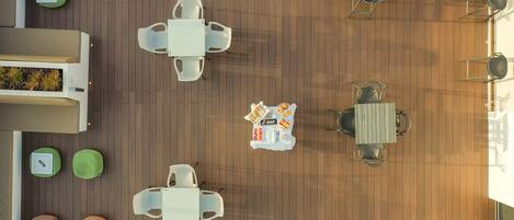 An outdoor seating area with multiple tables and chairs, arranged in a circular pattern around a central table with a tray of food.