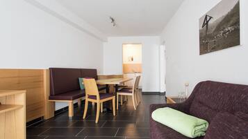 Een moderne kamer met een houten bank, een paarse bank, een eettafel met stoelen en een schilderij aan de muur.