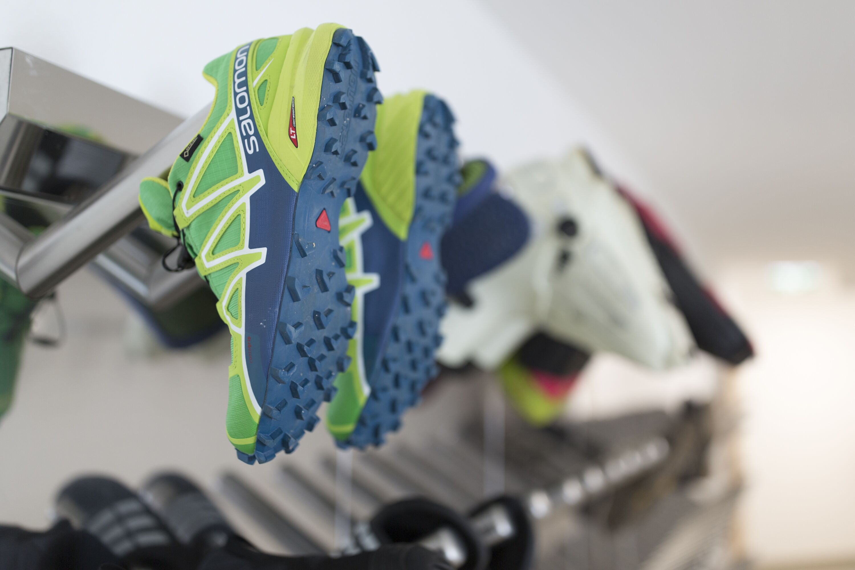 A pair of athletic shoes with a green and blue design, hanging on a rack.