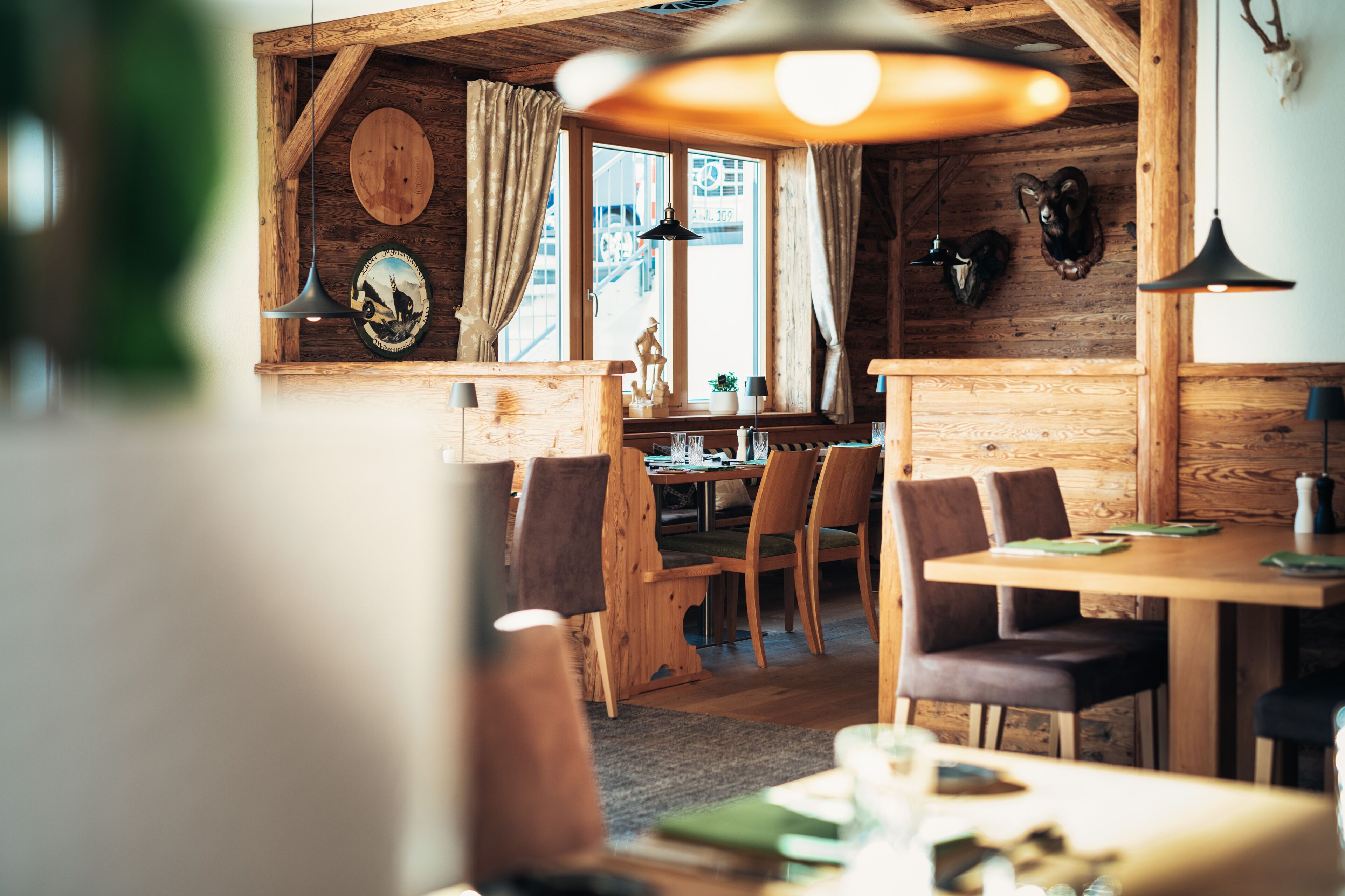 A rustic wooden interior with a dining area, wooden walls, and a large window.
