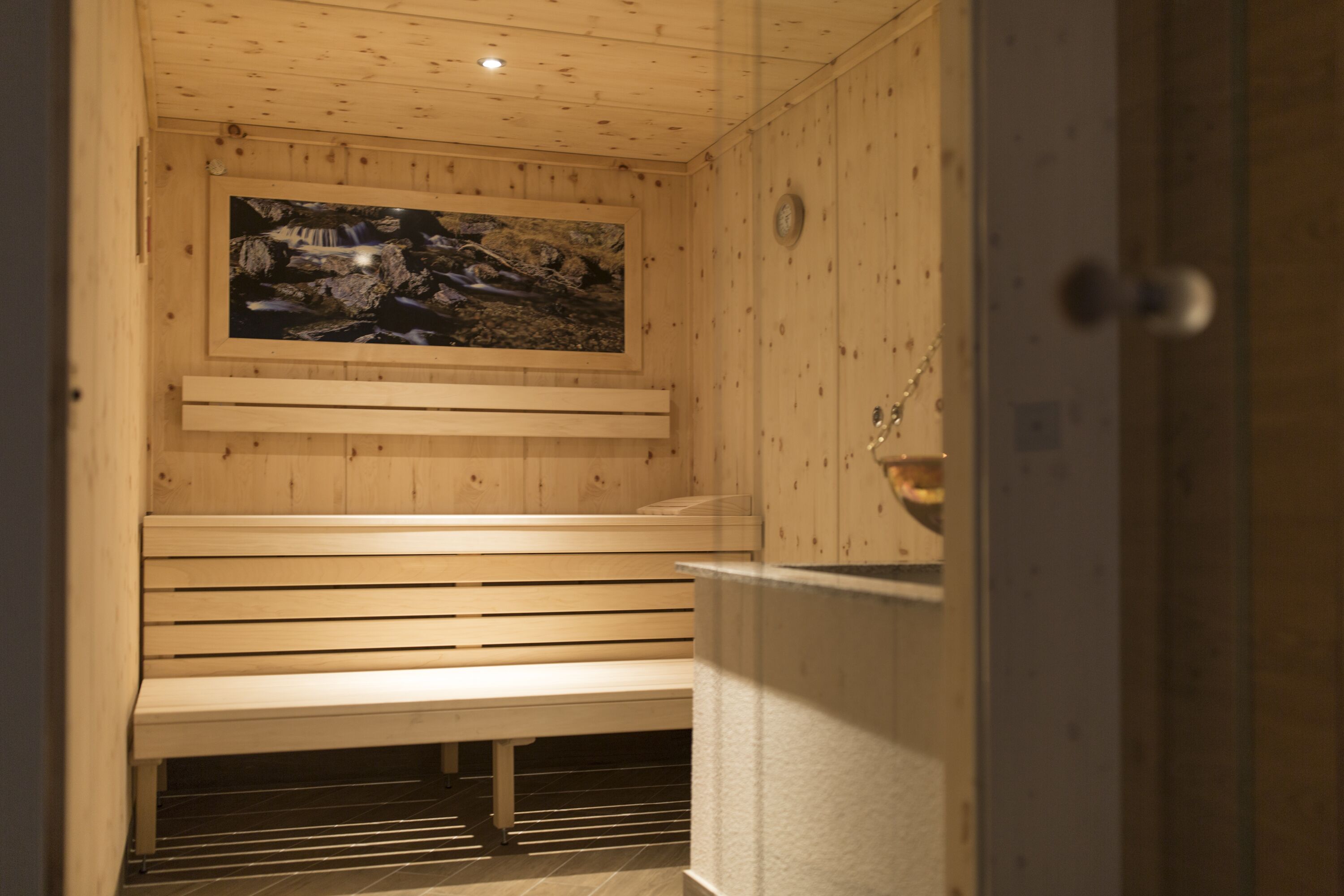 Una sauna de fusta amb una banca i una fotografia encadrada a la paret.