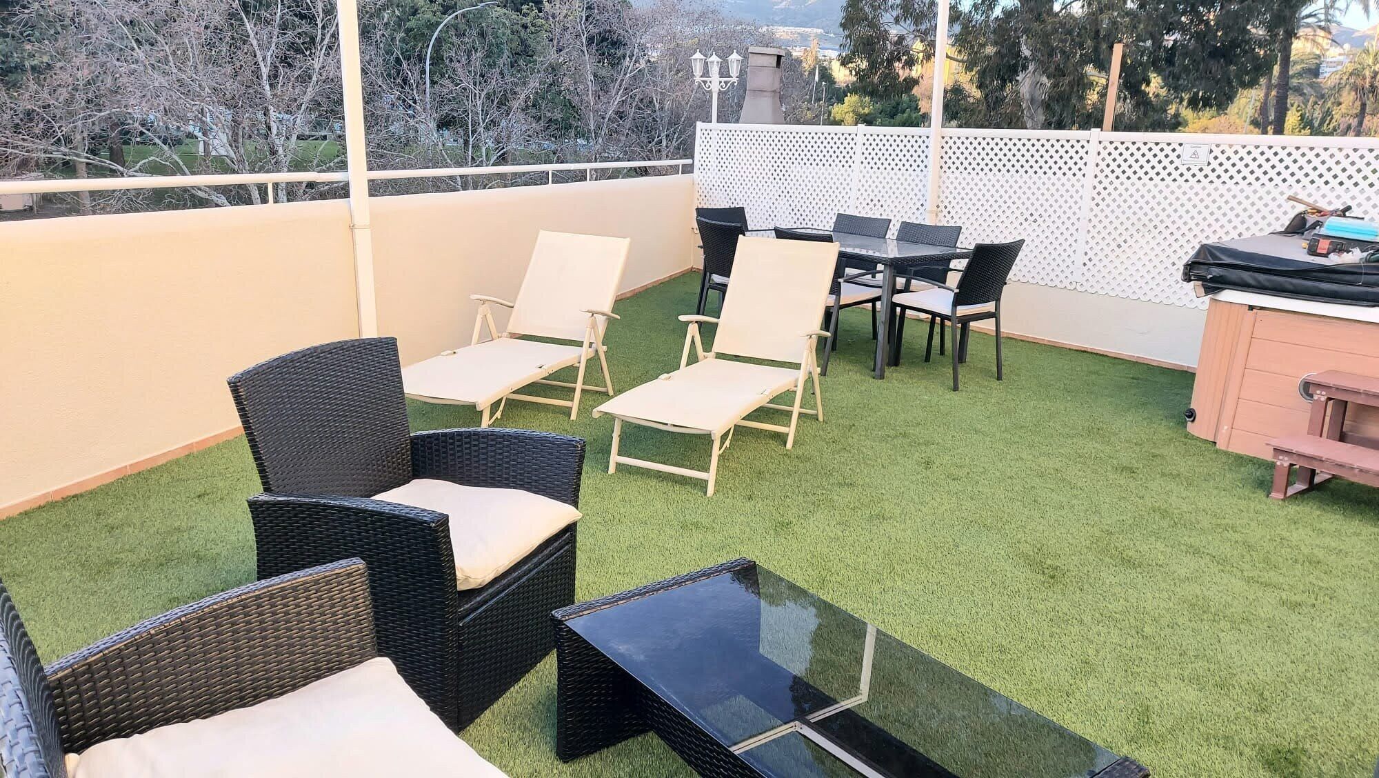 Eine Terrasse mit Korbmöbeln, einem Glastisch und einem Holzschrank.