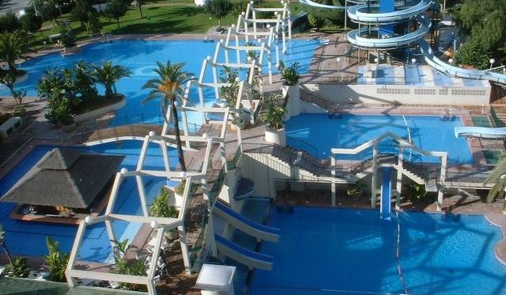 Ein Resort mit mehreren Schwimmbecken, einer Rutsche und einem großen zentralen Pool.