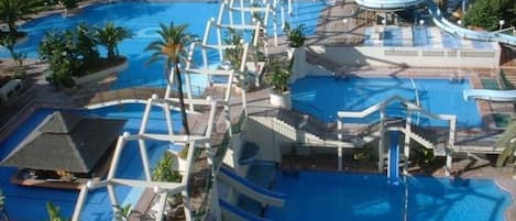 A resort with multiple swimming pools, a water slide, and a large central pool.