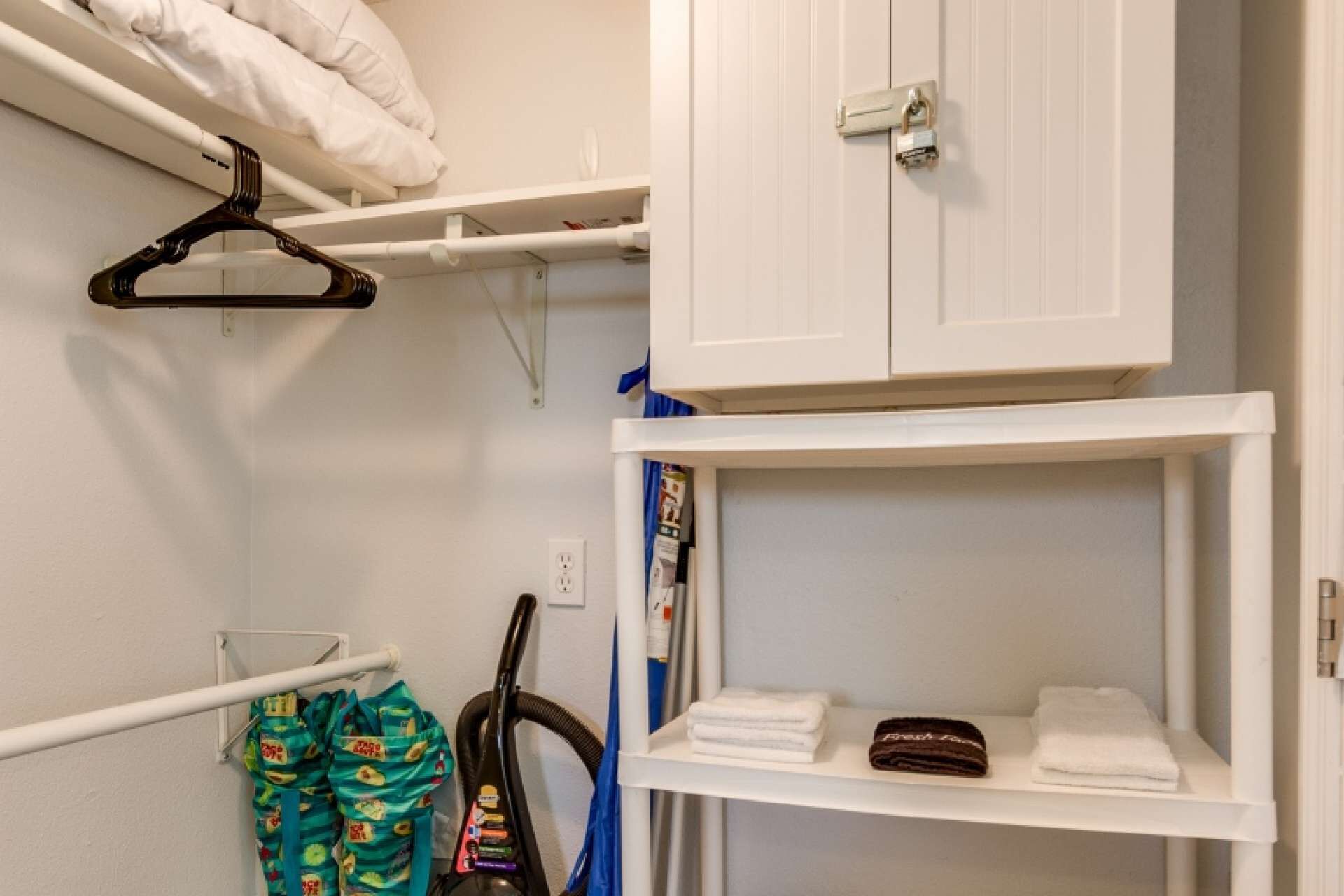 Un baño con un mueble blanco, un perchero y una repisa con toallas dobladas.