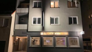 Un edificio con un cartello che riporta "City Vibes Hotel & Bistro" e tre vetrine etichettate "City Vibes", "Bistro Lounge" e "Cafe-Bar".
