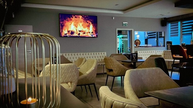 Un'area lounge moderna con poltrone in pelle, un tavolo e un murale raffigurante un camino.