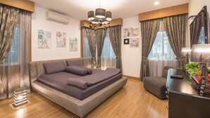 Un dormitorio moderno con una cama grande, un sofá pequeño, un escritorio con lámpara y un televisor.
