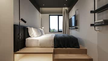 Une chambre à coucher moderne avec un lit, une télévision et une fenêtre.