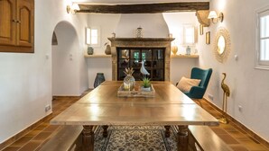 A dining area with a wooden table, a blue chair, and a rustic fireplace. - La Bastide du Riou (Bargemon)