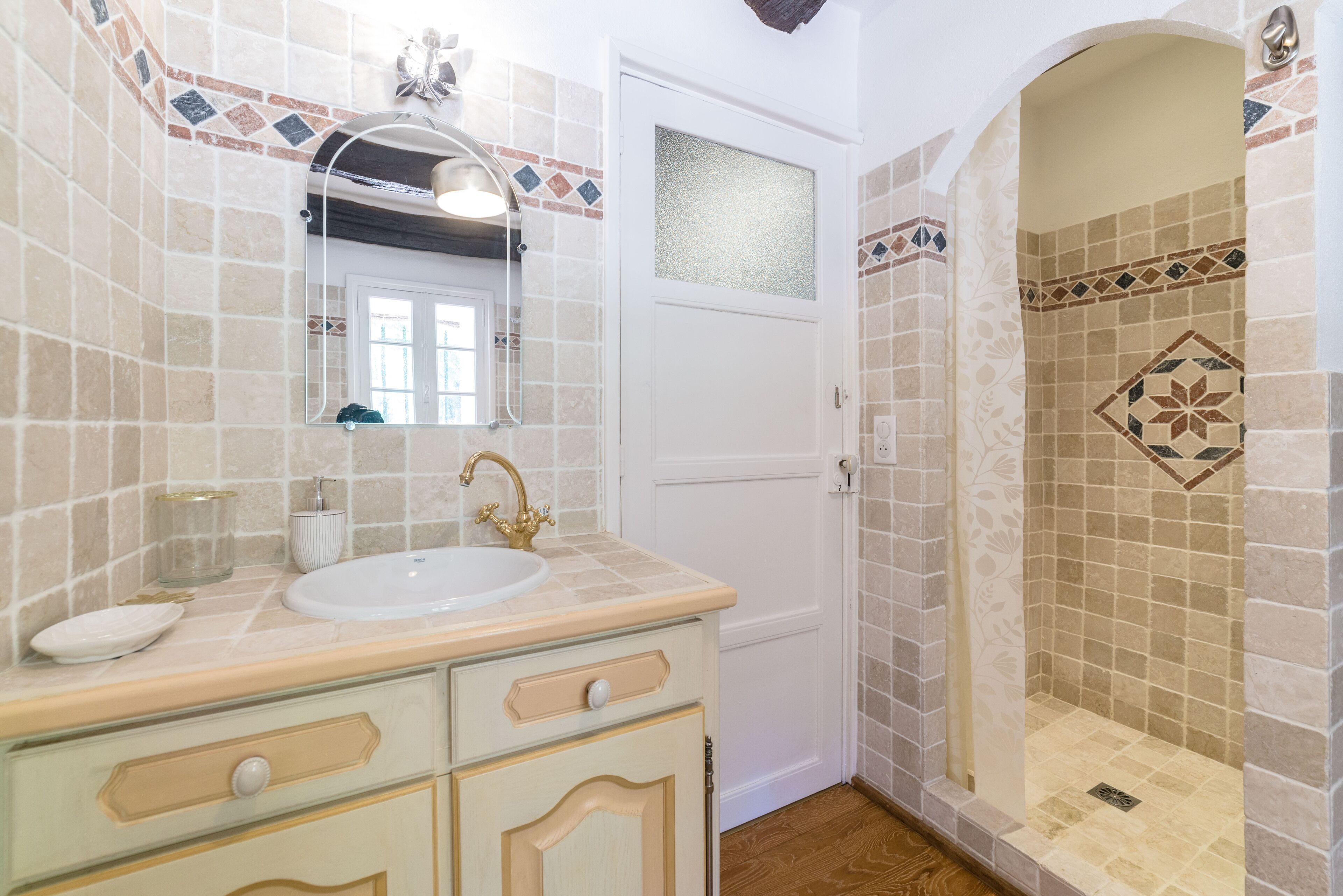 A bathroom with a sink, mirror, and shower area.