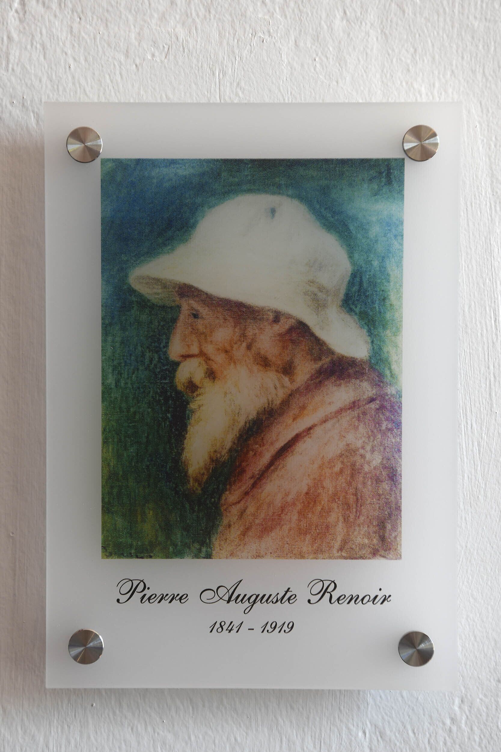 A framed portrait of a man with a white hat and beard, signed "Pierre-Auguste Renoir 1841-1919" below.