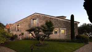 A stone building with a well-maintained lawn, a large tree, and a tall, narrow tree. - Bastide Des Demoiselles (Roussillon)
