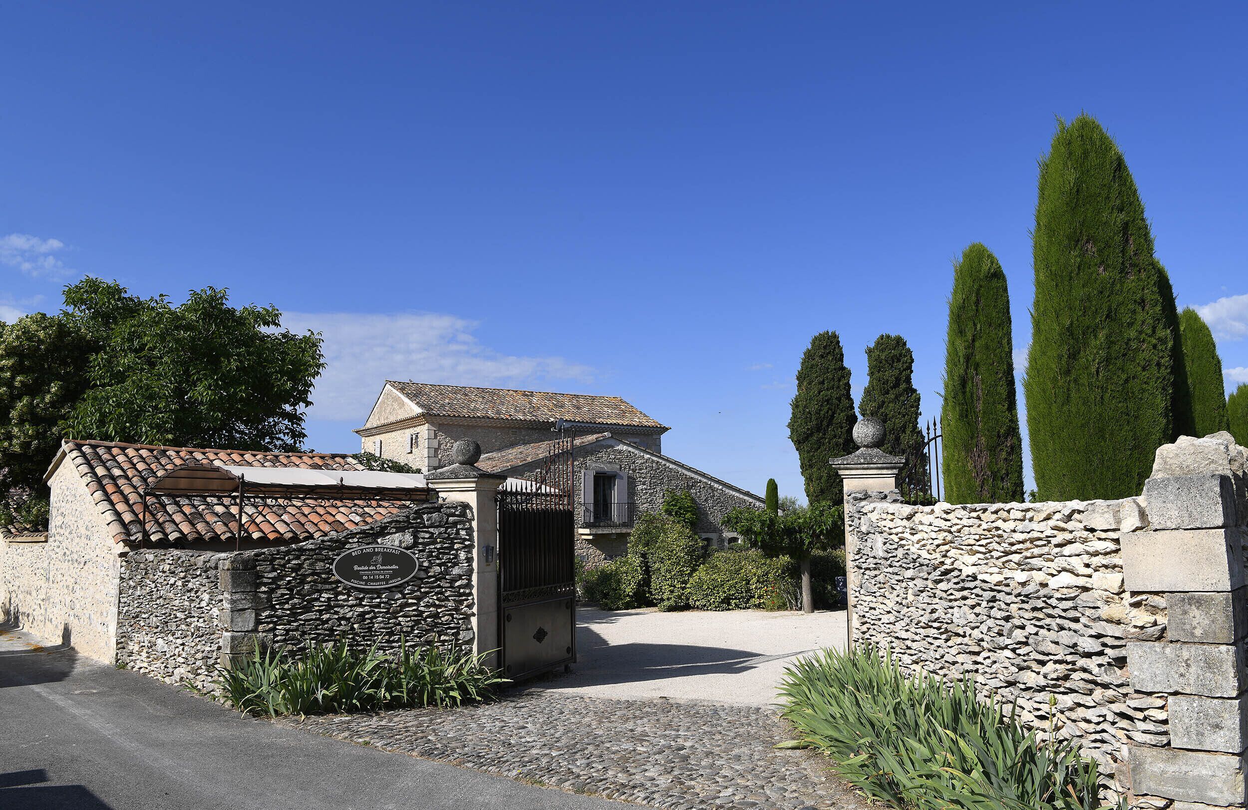 A stone building with a tiled roof, a stone wall, and a gate.