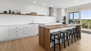 Een moderne keuken met witte kastjes, een houten aanrechtblad en een ingebouwde kookplaat.
