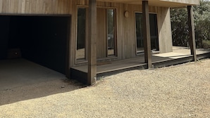 Een modern gebouw met een houten gevel, grote ramen en een grindpad.