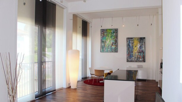 Eine moderne Kunstgalerie mit Holzböden, einem großformatigen abstrakten Gemälde und einer minimalistischen Sitzecke.