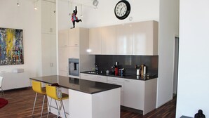 Eine moderne Küche mit weißen Schränken, einer schwarzen Arbeitsplatte und einer zentralen Kochinsel mit gelben Stühlen.