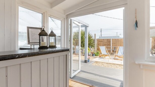 A kitchen with a wooden countertop, two lanterns, and a view of an outdoor deck with chairs and a wooden fence.