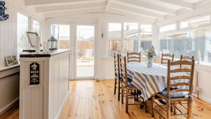 A dining area with a table set for four, wooden chairs, and a view through a glass door to an outdoor patio.