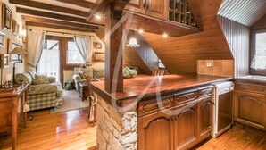 A spacious living area with a wooden staircase, stone walls, and a cozy seating area with a sofa and armchairs. - Sarrahèra (Baqueira)