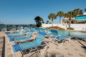 A poolside area with blue lounge chairs and a clear view of the ocean. - Majestic Beach 2-1501 - 1977694 (Panama City Beach)