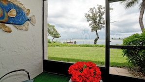 Quarto com vista para um lago, um barco e um arranjo de flores vermelhas.