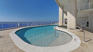 A pool with a clear view of the ocean, surrounded by a white railing and a covered area with lounge chairs. - Palazzo 1604 (Panama City Beach)